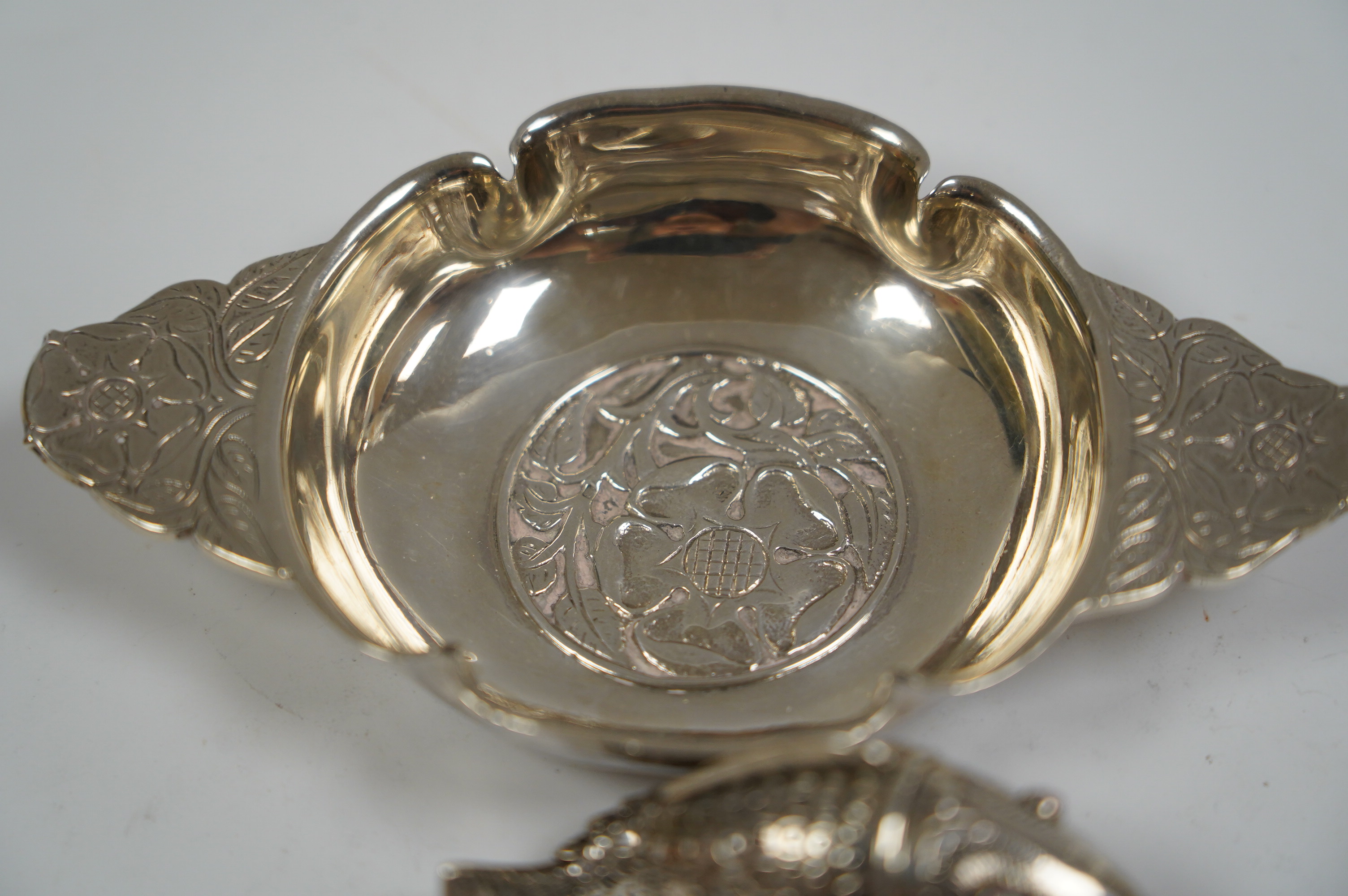 A George V foliate engraved silver quaich by Robert Edgar Stone, London, 1936, 12.2cm, together with a Norwegian 830 standard white metal articulated fish pill box, 60mm. Condition - fair to good